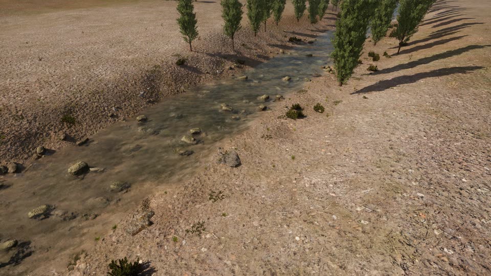 High view down onto a shallow river with scattered boulders, a dusty bank with small shrubs, and a row of poplars along the far bank.