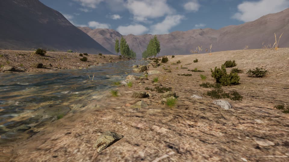 Eye-level view along a river margin: rippling water on the left, stones and grass tufts along the edge, shrubs on a dusty bank, poplars and bare mountains ahead.